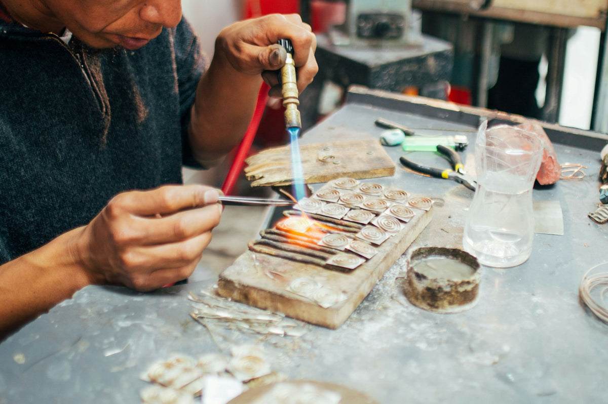 A craftsman soldering silver at a workbench