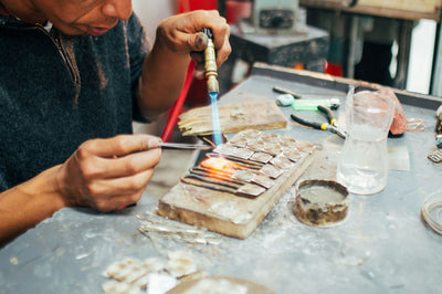 A craftsman soldering silver at a workbench